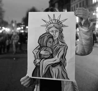Cross Lady Liberty comforts refugee child. Seen in London at rally against Trump's travel ban, 30 Jan 2017. (Alisdare Hickson from Canterbury, United Kingdom (CC-SA))